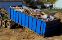 Services 3 Large blue roll-off dumpster being delivered by a tilt-bed roll-off truck
