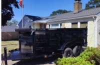 Services 2 Compact black dump trailer parked safely on residential paved driveway
